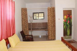 Un dormitorio con una cama, una silla y una ventana en Kanthalloor Homestay Snow White Holiday Homes, en Kanthalloor