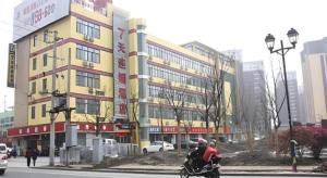 a man riding a motorcycle in front of a building at 7 Days Inn Changzhou North Station in Changzhou