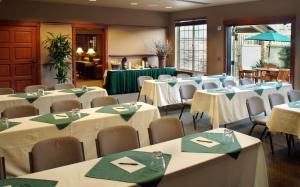 Larkspur Landing Sacramento-An All-Suite Hotel في سكرامنتو: غرفة مليئة بالطاولات والكراسي بمناديل خضراء