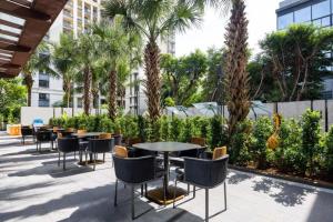 un patio avec tables, chaises et palmiers dans l'établissement Four Points by Sheraton Haikou International Airport, à Haikou