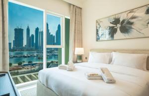 a bedroom with a white bed with a large window at Zapbed House -Elegant 1 BR Apartment Grand Bleu Emaar Beachfront in Dubai