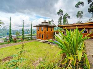 ein Holzhaus mit einem Rasenplatz davor in der Unterkunft Hotel O Artana Bed and Breakfast.NearSitu Cileunca in Pengalongan
