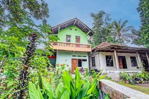 ein grünes Haus mit einem Balkon im Garten in der Unterkunft SPOT ON 93592 Pondok Backpackers Ardafa Jogja in Manisrenggo