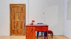 einen Holztisch mit zwei Stühlen und einer Holztür in der Unterkunft SPOT ON 93592 Pondok Backpackers Ardafa Jogja in Manisrenggo