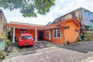ein rotes Auto, das vor einem orangefarbenen Haus geparkt ist in der Unterkunft OYO 92759 Penginapan Piji Kembar in Tawangmangu