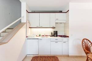 a white kitchen with a sink and a staircase at Golf Ranch, 1Er Stock in Ascona