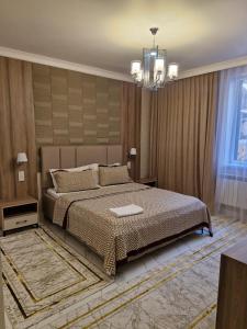 une chambre avec un grand lit et un lustre dans l'établissement Gostinitsa Grand, à Kyzylorda