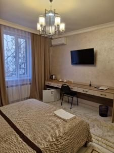 une chambre avec un lit, un bureau et une télévision dans l'établissement Gostinitsa Grand, à Kyzylorda