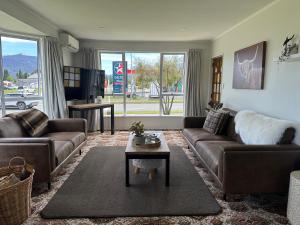 a living room with brown couches and a table at Cosy & close to town in Te Anau