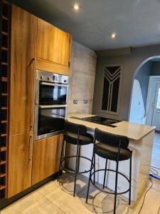 une cuisine avec un comptoir et deux tabourets de bar dans l'établissement Home at Richmond - Conifer Crescent, à Nottingham 10 autres photos