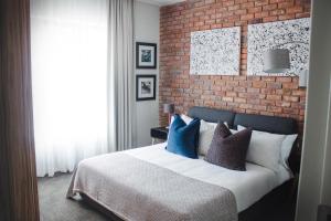 a bedroom with a brick wall and a bed with pillows at Iconyc Apartment in Brentwood Park +28 photos