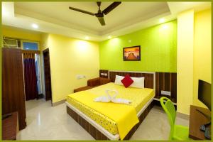 1 dormitorio con 1 cama amarilla y 2 toallas en Jagannath Temple Shashi Palace Resort - Fully Air conditioned# Free Wifi And Room Service #Budget Class Best Hotel IN Puri, en Puri