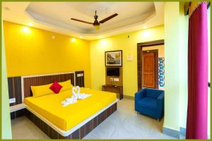 Un dormitorio amarillo con una cama y una silla azul. en Jagannath Temple Shashi Palace Resort - Fully Air conditioned# Free Wifi And Room Service #Budget Class Best Hotel IN Puri, en Puri