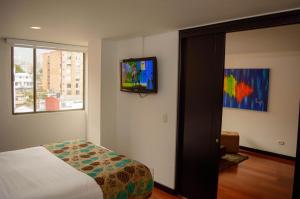 une chambre avec un lit et une télévision au mur dans l'établissement Hotel Confort 80 Zona Rosa By Hoteles Confort80, à Bogotá