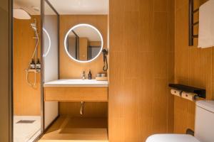 ein Badezimmer mit Waschbecken und Spiegel in der Unterkunft JI Hotel Guangzhou Sports Center Tianhe North Road in Guangzhou + 38 Fotos