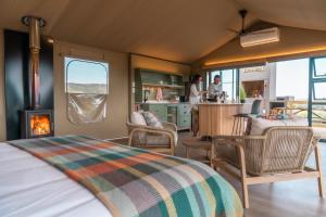 a bedroom with a bed and a kitchen with a fireplace at AfriCamps Klein Karoo in Oudtshoorn