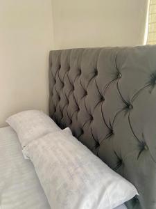 een bed met een gewatteerd hoofdeinde en een wit kussen bij Lajoy Executive Lodge in Lusaka +1 foto