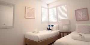 Un dormitorio con dos camas y una silla dentro. en The Helm Unit 1 22 Voyager Close, en Nelson Bay