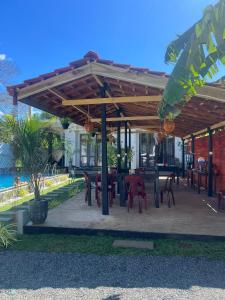 eine Terrasse mit Tischen und Stühlen unter einer hölzernen Pergola in der Unterkunft Indunil Family Residence With Pool Hiriketiya in Dikwella