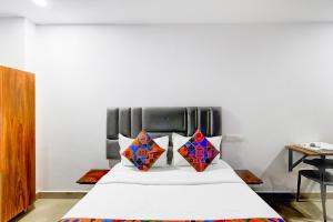 a bedroom with a white bed with colorful pillows at FabHotel Lorwen in Hyderabad