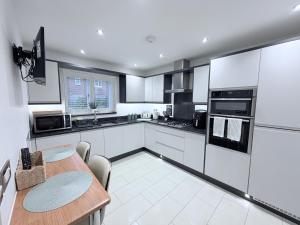 une cuisine avec des armoires blanches et une table en bois dans l'établissement Luxury House - sleeps up to 6 - near Nec, à Meriden