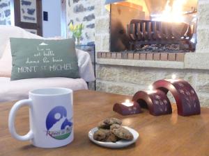a table with a coffee mug and cookies on it at Maison Sérénité et Nature près du Mont Saint Michel in Braffais