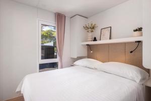 a bedroom with a white bed and a window at Pinadria Adriatic Coast in Baška Voda