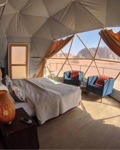 a bedroom with a bed and two chairs in a tent at Star Magic Camp in Wadi Rum