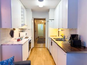 a kitchen with white cabinets and a wooden floor at Large Group Fireside Cabin in Rovaniemi +17 photos