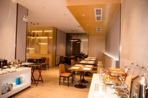 ein Restaurant mit Tischen und Stühlen in einem Raum in der Unterkunft Borrman Hotel Guangzhou East Station Meihuayuan Subway Station Branch in Guangzhou