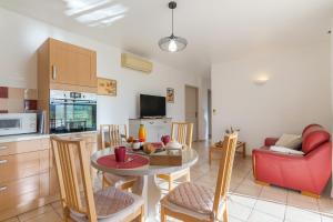 Le Petit Etang في جيرو-لي-بان: مطبخ وغرفة معيشة مع طاولة وكراسي