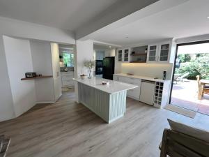 eine Küche mit weißen Schränken und einem großen Fenster in der Unterkunft SeaSalt Escape in Plettenberg Bay