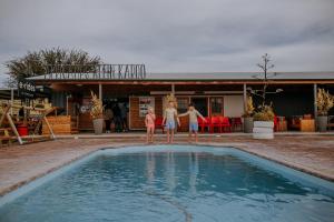 three people standing in front of a swimming pool at AfriCamps Klein Karoo in Oudtshoorn