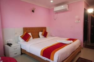 a bedroom with a large bed with pink walls at Hotel Ganga Sagar in Kathmandu
