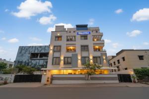 a white building with a blue sign on it at Via Shahi Villa in Pune