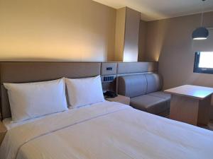 a bedroom with a large white bed and a couch at 丰居中壢 Via Hotel Zhongli in Zhongli