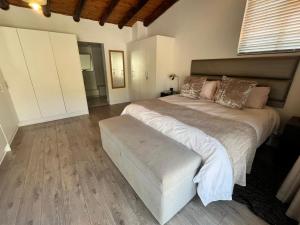 ein Schlafzimmer mit einem großen Bett mit einer Bank daneben in der Unterkunft SeaSalt Escape in Plettenberg Bay