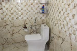 La salle de bains est pourvue de toilettes blanches et de murs en marbre. dans l'établissement Mysterious Kutla Cottage,Kutla, Tosh, à Chhorang 87 autres photos
