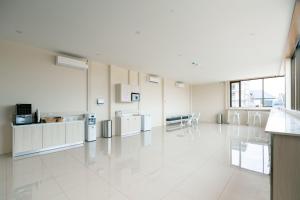 une grande pièce blanche avec une cuisine, des tables et des chaises dans l'établissement One Budget Hotel Chiangrai Bypass-West, à Ban Hua Khwai (1)