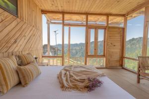 Jufri Hills Cottage في Jibhi: غرفة نوم بها سرير في غرفة بها نوافذ