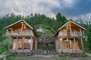 Jufri Hills Cottage في Jibhi: منزلين خشبيين كبيرين في الغابة