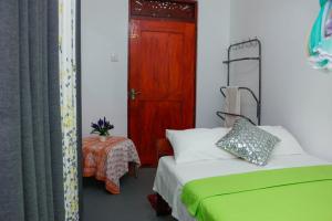 ein Schlafzimmer mit einem Bett und einem Tisch und einer Tür in der Unterkunft Mountain Breeze Inn Midigama in Midigama East