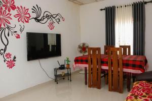 ein Wohnzimmer mit Fernseher und Tisch und Stühlen in der Unterkunft Mountain Breeze Inn Midigama in Midigama East