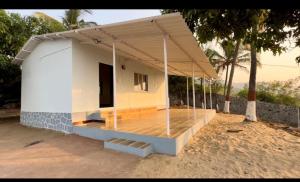 una piccola casa bianca con un portico su una spiaggia di Secret Shore N Tide Luxurious Suite , Sea Facing ad Alibaug