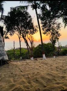 una spiaggia con palme e un tramonto sullo sfondo di Secret Shore N Tide Luxurious Suite , Sea Facing ad Alibaug