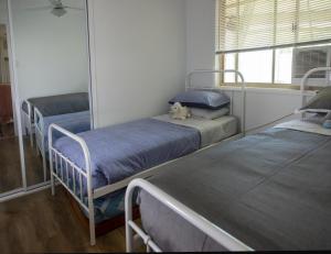 Ein Zimmer mit drei Betten und einem Teddybären darauf. in der Unterkunft Serene Saltair in Redland Bay