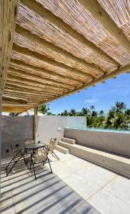 a patio with a table and chairs under a wooden roof at Patacho Brisa Mar - Triplex na Rota Ecológica dos Milagres in Pôrto de Pedras
