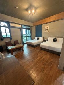 2 Betten in einem Zimmer mit Holzböden und Fenstern in der Unterkunft Bear&Best Homestay in Yuli