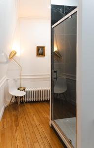 Una habitación con un espejo, una silla y una lámpara. en Le Henri II - logements d'exceptions entièrement autonomes, en Le Mans