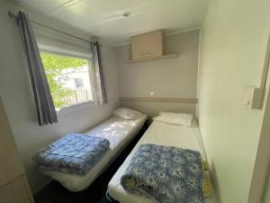 two beds in a small room with a window at Camping 3 étoiles - Piscine - eehhec in Landry